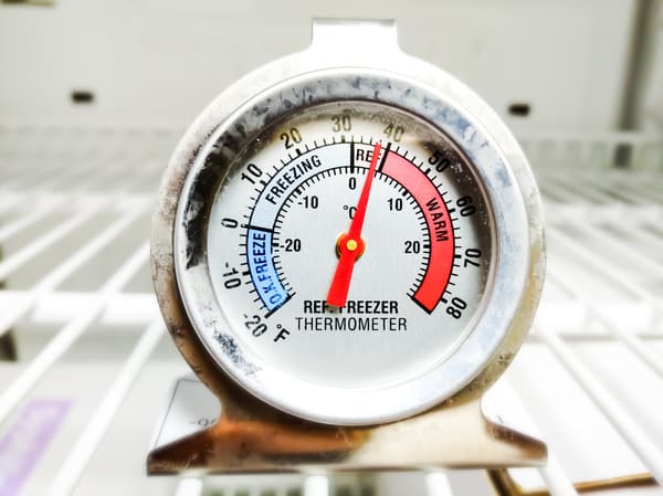 A close-up of an analog thermometer in a fridge